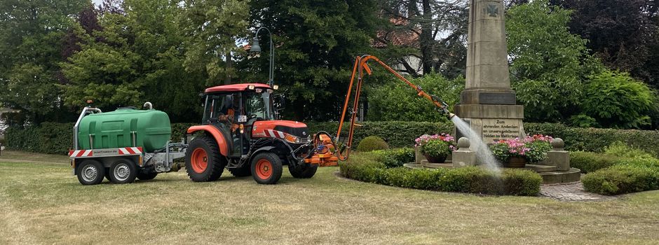 Bewässerung: Gespann aus Trecker mit Gießarm und Gießfasswagen im Gemeindegebiet
